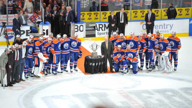 Edmonton Oilers players pose beside the Clarence S. Campbell Bowl