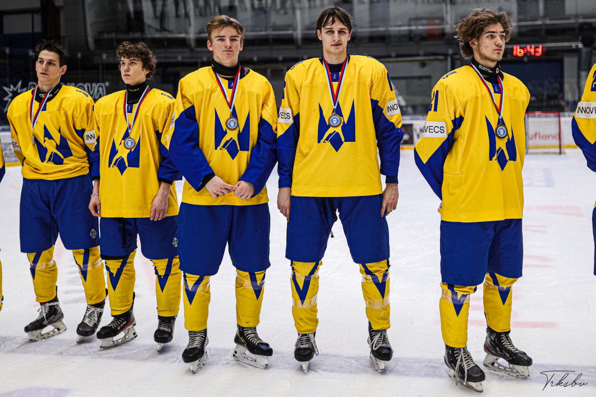 Members of a hockey team wearing yellow jerseys and medals.