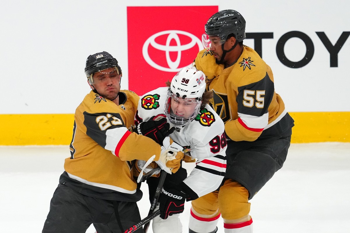 Connor Bedard gets squeezed by Alec Martinez (left, 23) and Keegan Kolesar (right, 55)